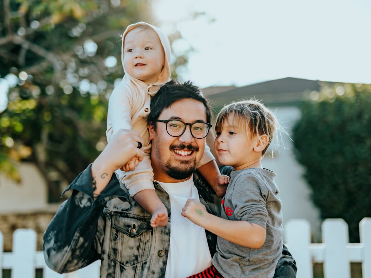 Un padre con sus dos hijos pequeños en el jardín de casa